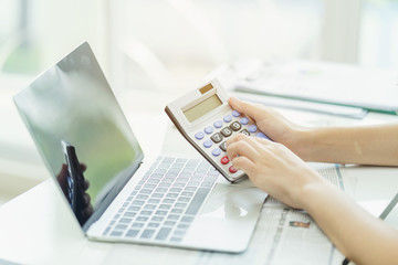 Accounting analyst calculate break even point by using financial report for banking investment. Using calculator and computer laptop to collect financial data to analyse profit for executive decision