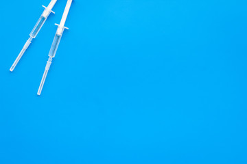 Vaccination, immunization. Syringe with colored medicament on blue background top view copy space