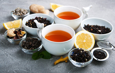 Cups of tea with aromatic dry tea in bowls