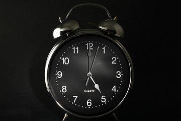 Old retro alarm clock with the hands set to 5:00 am or pm