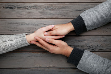 Female and male hand holding each other on grey background
