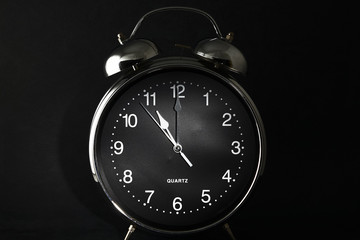 Old retro alarm clock with the hands set to 11:00 am or pm
