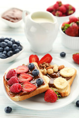 Toasts bread with berries and jug of milk on wooden table