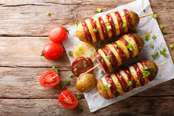Shish kebab from potatoes with sausages on skewers close-up. horizontal top view