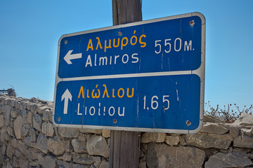Greek road sign direction - written in Greek and in its Latin alphabet transcription. Shot taken in Schinoussa island
