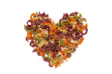 Dried pasta in heart shape top view. Colorful vegetable pastas on isolated background