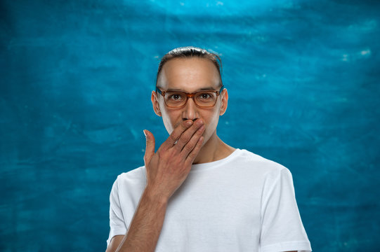 Portrait of young stylish hipster guy wearing glasses looking at the camera on blue background