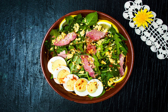 Dandelion salad with eggs meat and lemon in a bowl