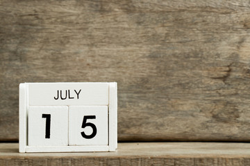 White block calendar present date 15 and month July on wood background