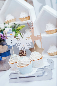 muffins are decorated of image of a deer, snowflakes and a snowman are standing  on the sleigh
