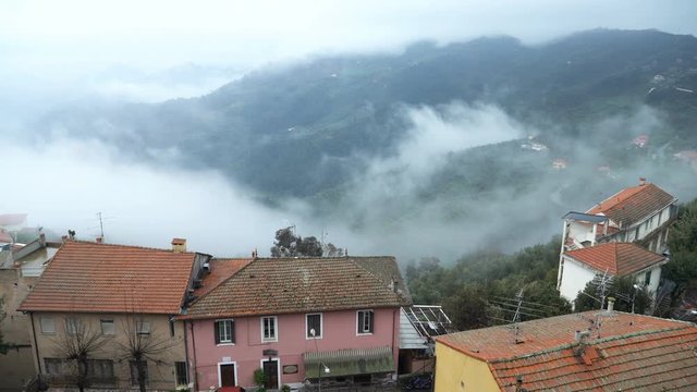 Early foggy morning in the Alpine town. Fog from the mountains makes its way along the medieval streets. Perinaldo, Liguria, Italy.