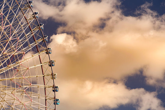Path of gaint ferris wheel aginst white clouds over blue sky