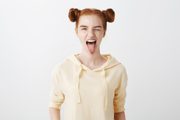 Cute redhead show her wild side. Indoor shot of attractive caucasian ginger girl with two buns...