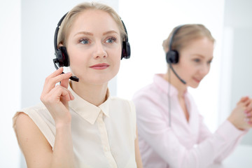 Image of bright call center. Focus on young beautiful woman in a headset