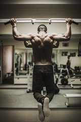 Fototapeta na wymiar man in sportswear makes exercises for back in the gym