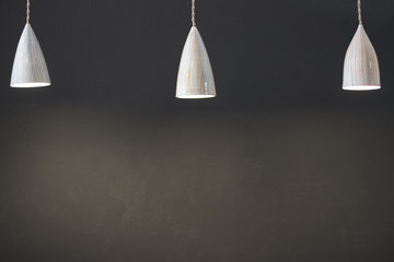 Three hanging modern lamps illuminate the gray wall, a copy of space, space for text