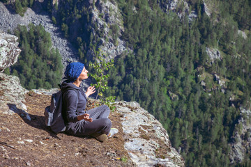 Woman hiker sitting on top of a mountain and relax in sunny summer day