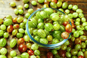 Gooseberries in a plate on a wooden background