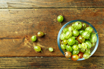 Gooseberries in a plate on a wooden background