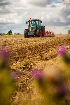 A tractor ploughing a field of crops. Shallow depth of field with selective focus on the tractor.