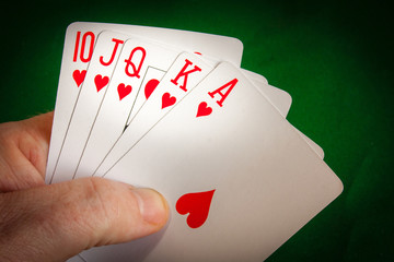 Poker player holding a hearts royal flush with hearts.