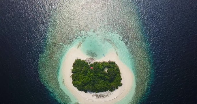 Aerial view of a desert island with a clear and transparent sea and a pristine beach. Concept of: holidays, maldives, dream landscapes.