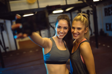 Fototapeta na wymiar Two good looking girls are taking selfie in the gym