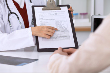 Close up of a female doctor pointing into an application form while consulting patient