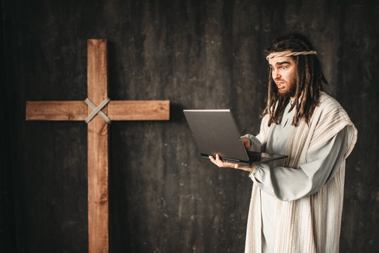Man in the image of Jesus Christ uses laptop