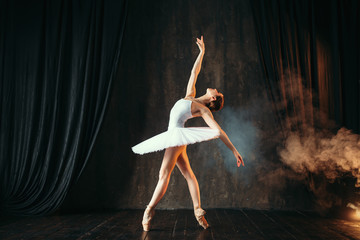 Naklejka premium Balerina w białej sukni tańczy w klasie baletu