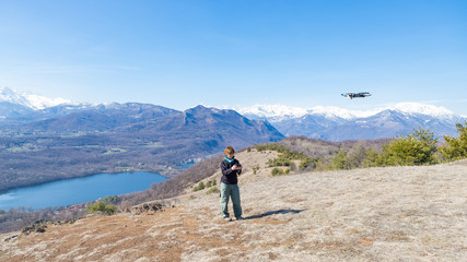 woman flying drone outdoors with remote control. One person in scenic landscape driving drone...