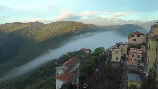 Early foggy morning in the Alpine town. Fog from the mountains makes its way along the medieval streets. Perinaldo, Liguria, Italy.