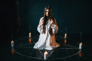 Woman sitting in the center of pentagram circle