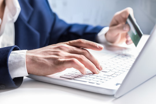 Man hands typing on the keyboard of laptop holding credit card, close-up of online shopping
