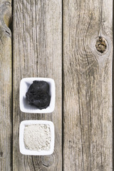 gray cosmetic clay powder and black mud on old wood texture