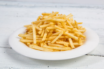 Sticks of french fries on white plate