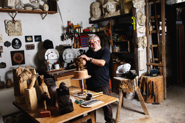 Senior sculptor working on his clay sculpture in his workshop.