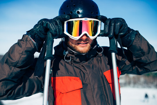 Male skier in helmet puts on glasses, front view