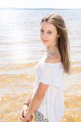 Fototapeta na wymiar Portrait of cheerful natural young girl with long hair on water sand sea beach