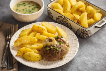 Braised veal shank served with baked potatoes and onion sauce.