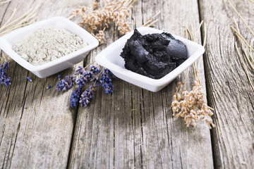 cosmetic clay powder and mud with dried lavender flowers on old weathered wooden table background