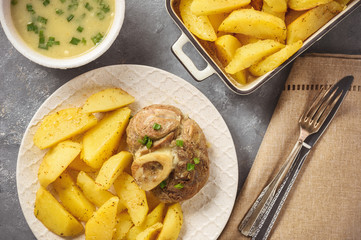 Braised veal shank served with baked potatoes and onion sauce.