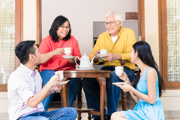 Fototapeta premium Side view of young man and woman visiting parents at home in the afternoon at tea time