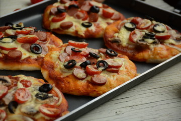 Italian pizza with cheddar cheese, mushrooms, black olives and sausage on white wooden background 