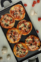 Italian pizza with cheddar cheese, mushrooms, black olives and sausage on white wooden background 