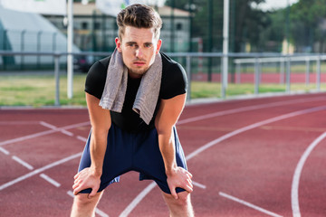 Young athlete stretching on racing track before running