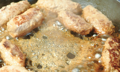 Tasty meat cutlets are fried in oil in a pan. Close-up top view.