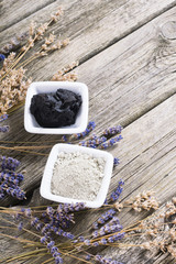 cosmetic clay powder and mud with dried lavender flowers on old weathered wooden table background