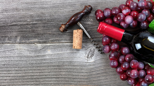 Dark bottle of red wine and grapes on vintage wooden planks
