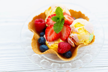 Beautiful homemade rainbow gluten free fruit  ice cream from strawberries, blueberries, raspberries, bananas pistachios in waffle basket. Summer healthy food and clean eating concept, copy space. 